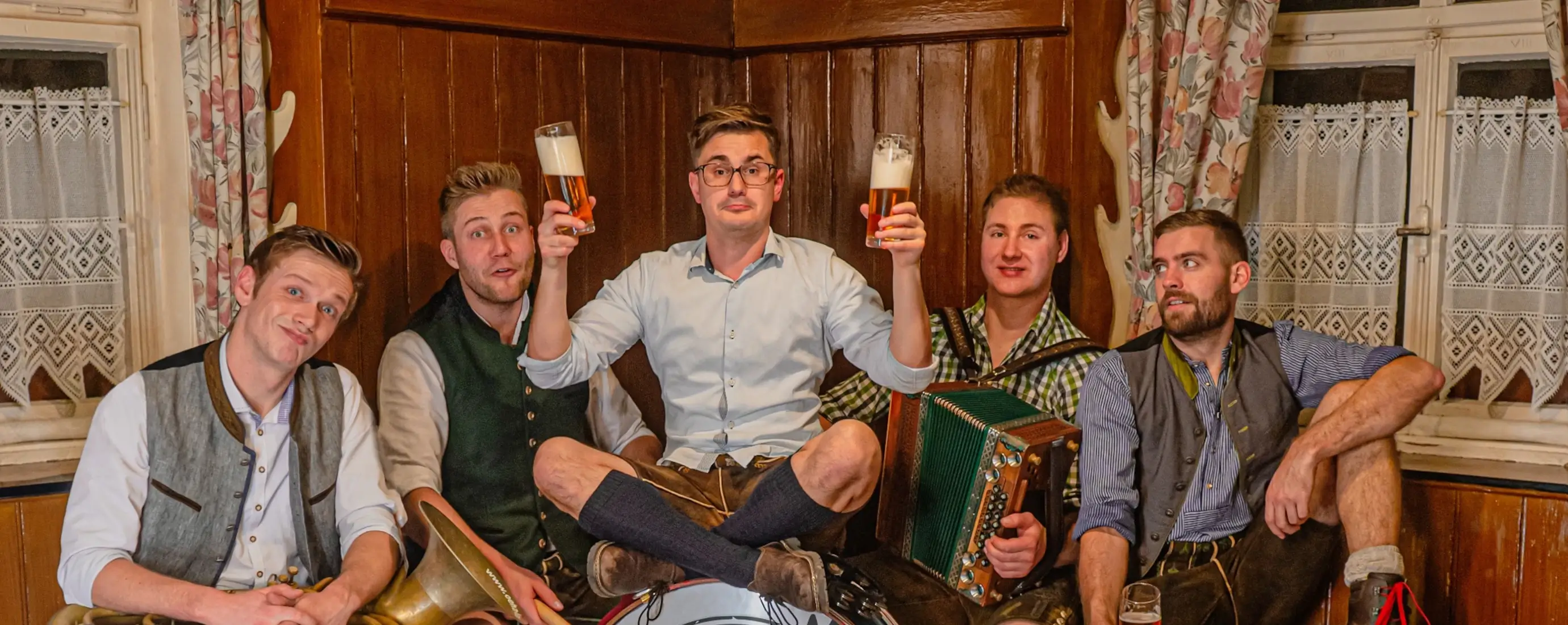 Ö'ha – die bayrische Partyband aus Breitenbrunn, fünf Musiker in Tracht mit Instrumenten und Biergläsern in gemütlicher Wirtshaus-Atmosphäre – perfekt für Volksfest, Gründungsfest oder FF-Jubiläum.