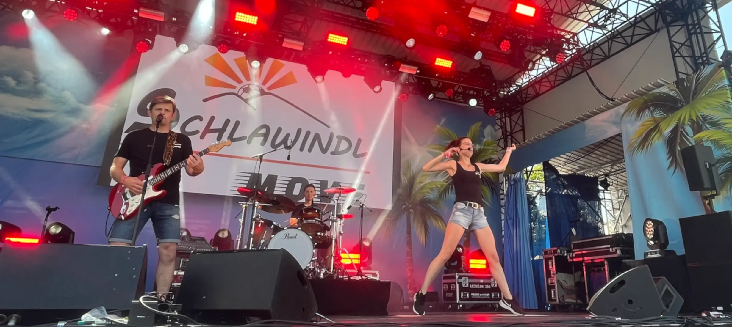 Schlawindl – die Kinder- und Jugendband aus Eichenried live auf der Bühne mit Sänger, Gitarrist, Schlagzeuger und Tänzerin, energiegeladene Show mit Lichteffekten.