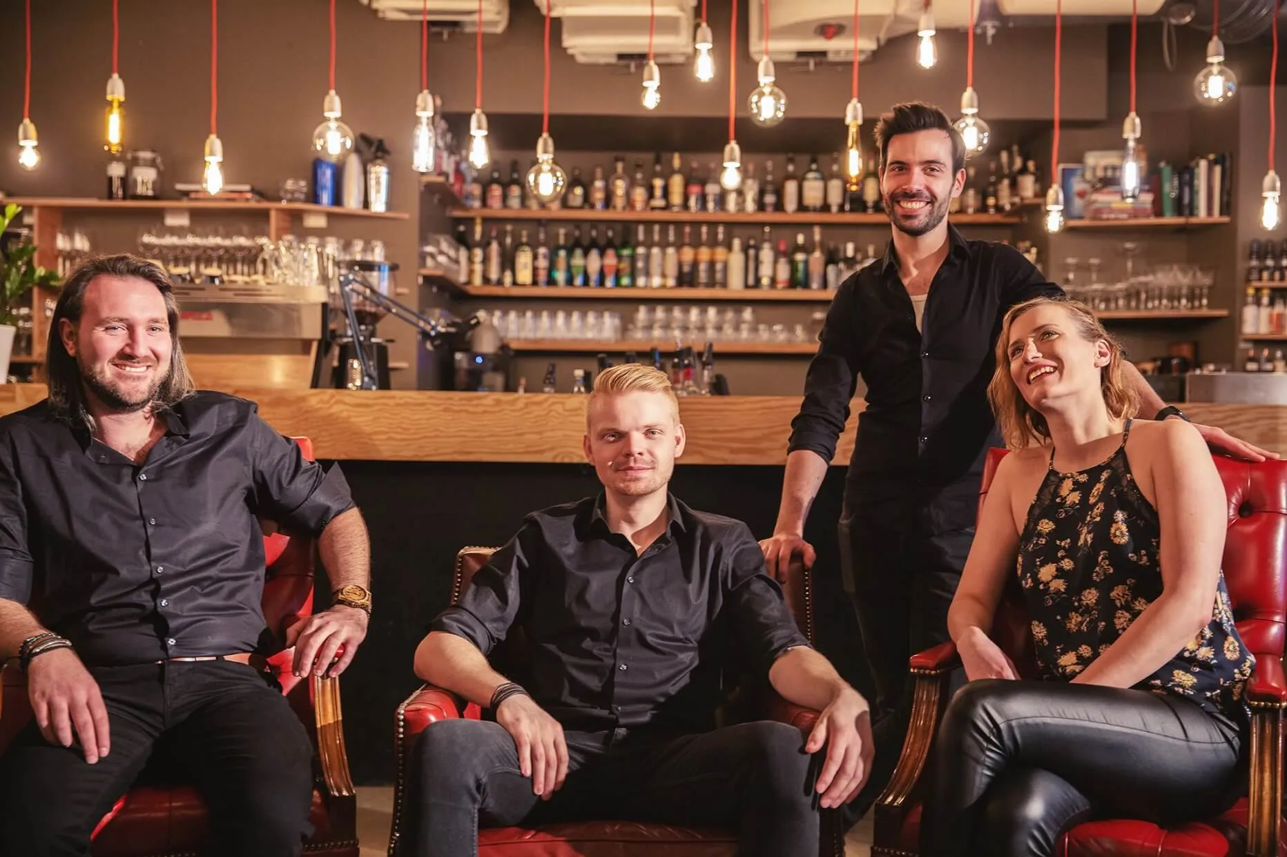 Die Partyband Whoobers chillig nebeneinander sitzend in einer Bar in Regensburg.