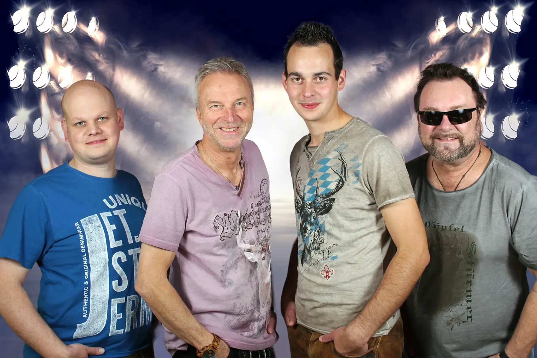 Die Gseea Wepsn – die bayrische Partyband aus Gößweinstein, vier Musiker in legeren Shirts posieren vor einem Bühnenhintergrund mit Lichteffekten.