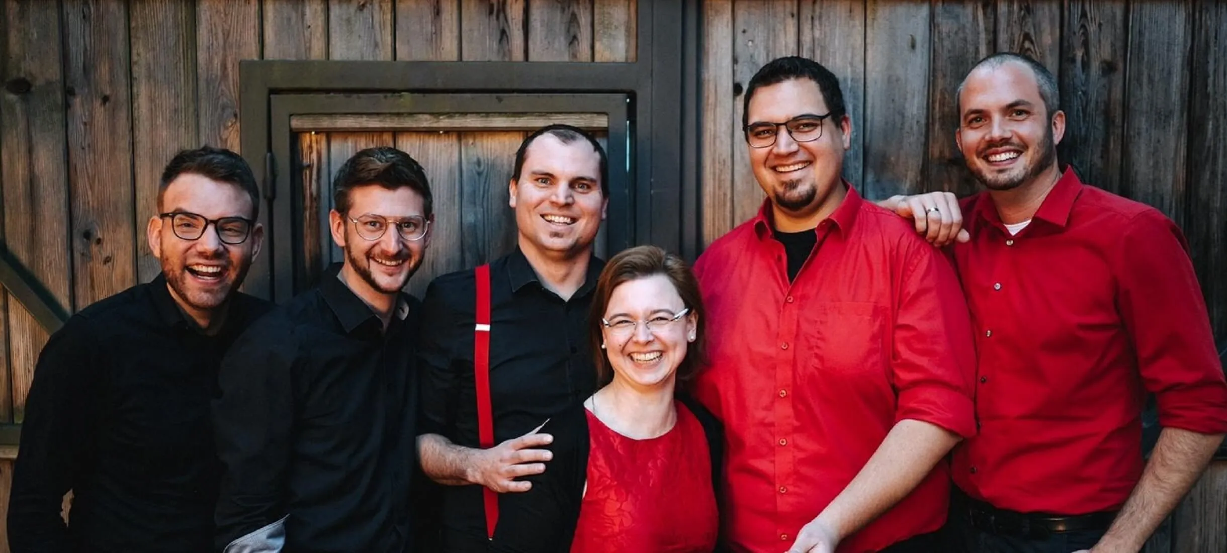 Die sechs Musiker der Riedenburger Partyband Hatphones stehen bei einer Hochzeit in Buch im Landgashthof Schneider vor einem rustikalen Stodl.