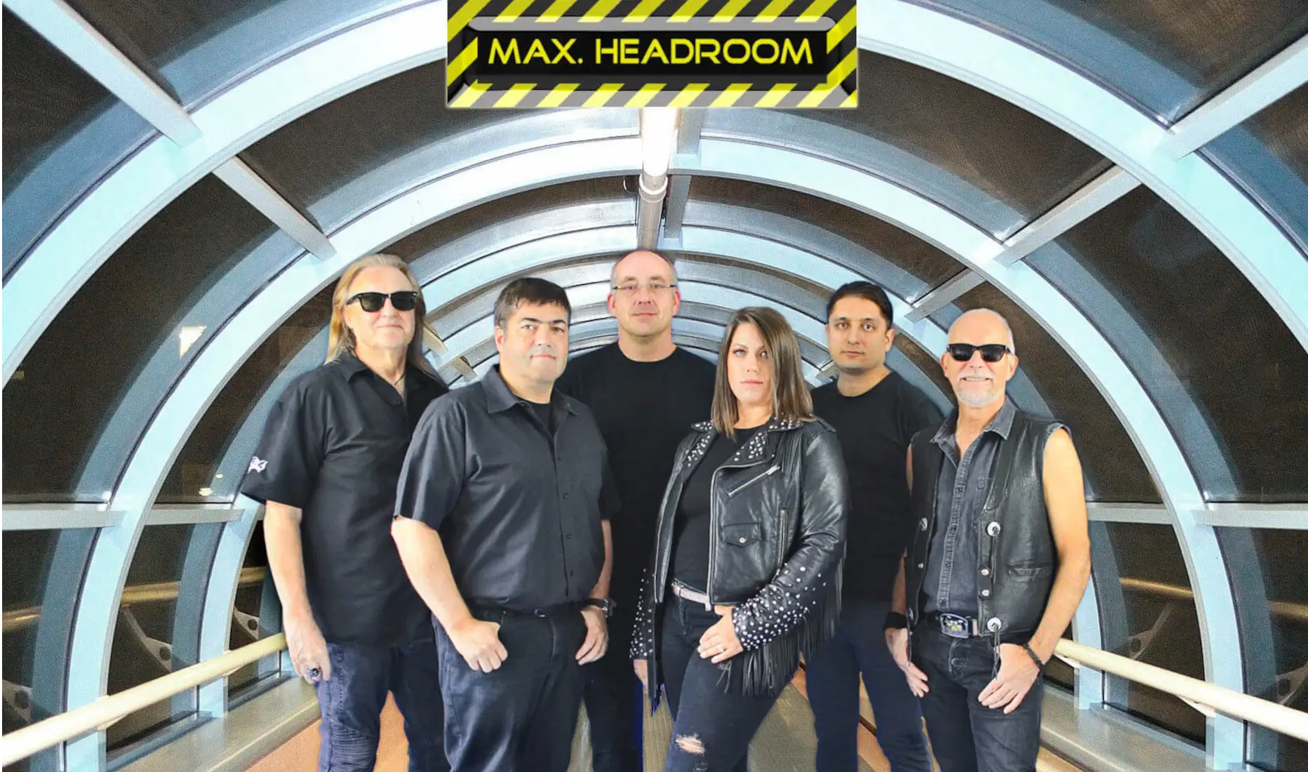 Die 6 Musiker der Partyband bzw. Rock und Blues Coverband Max Headroom stehen schwarz gekleidet nebeneinander und posieren für den Fotografen.
