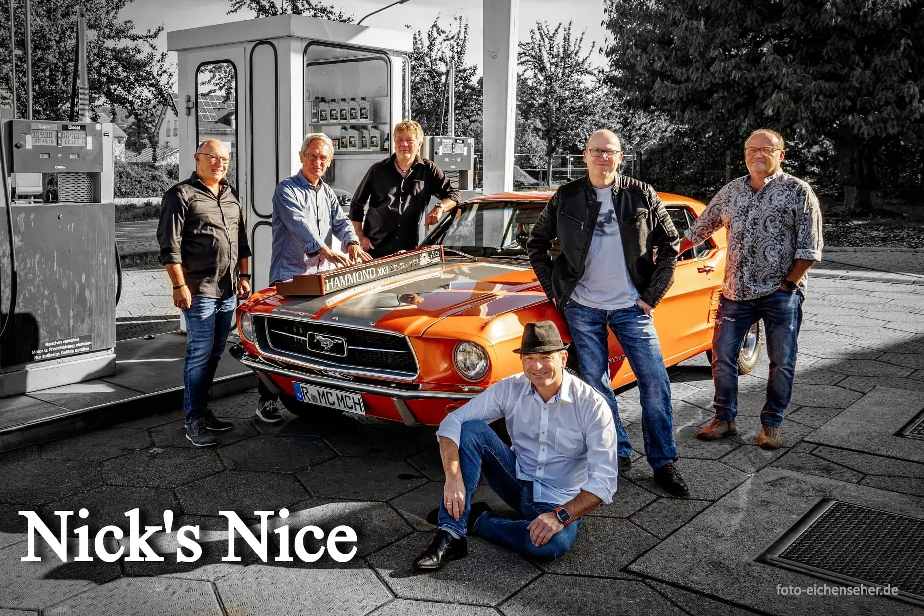 Die Classic Rockband Nick`s Nice vor einem Oldtimer an einer Tankstelle.
