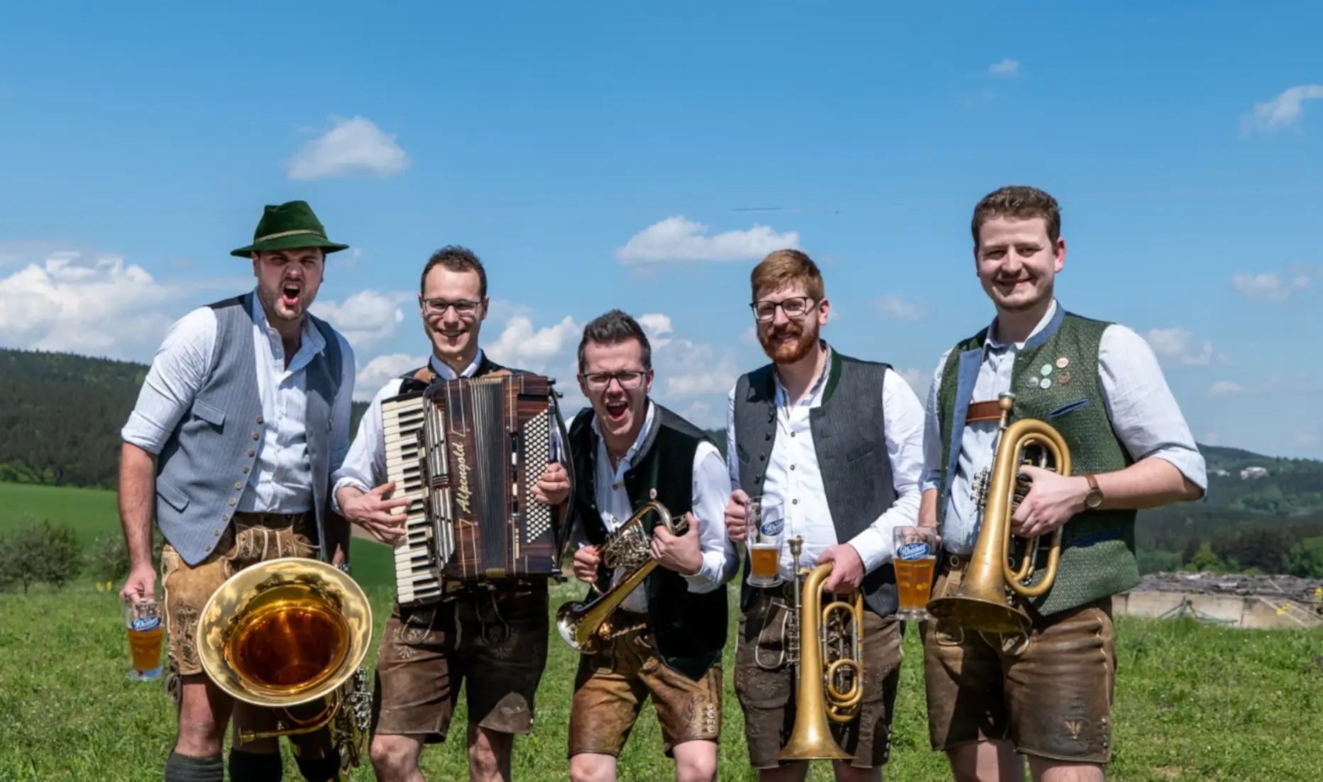 Die 5 Musiker der Rüscherl Muse stehend auf einer Wiese.