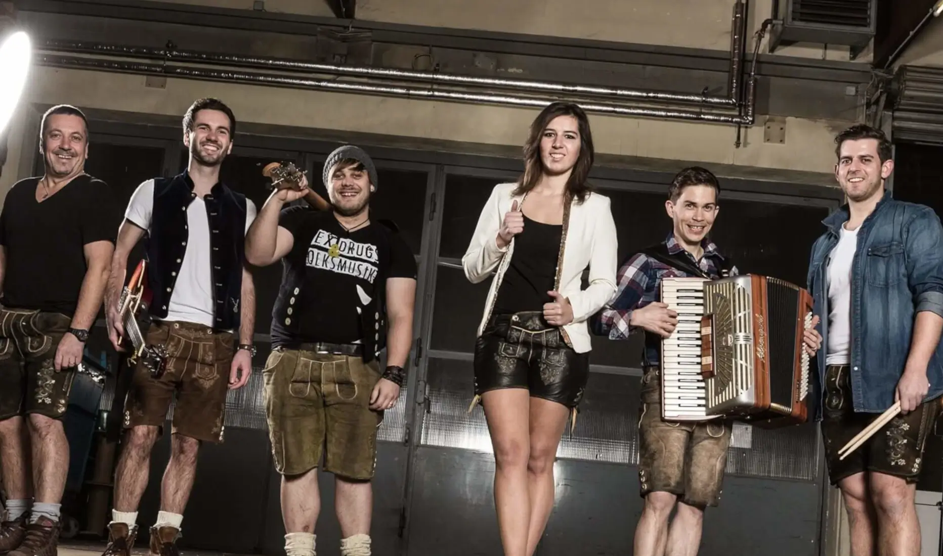 Die WoidRocker – die bayrische Partyband aus Prackenbach, sechs Musikerinnen und Musiker in Lederhosen und moderner Kleidung mit Gitarre, Akkordeon und Schlagzeug, bereit für Stimmung im Festzelt.