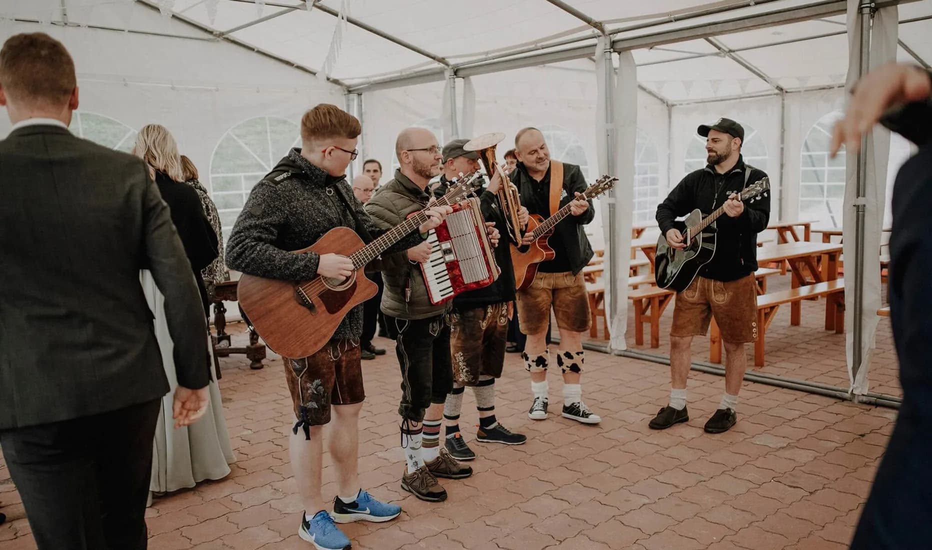 Die fünf Musiker der Bayrischen Partyband Wois Bois sitzend vor einer Bühne bei einer Hochzeit.