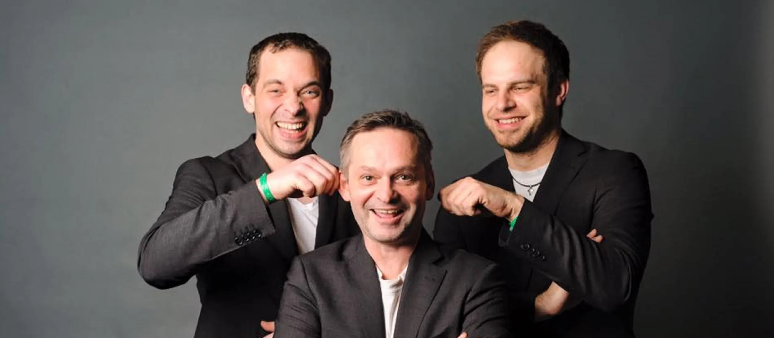 Die drei Musiker der Partyband Zechpreller stehend vor einer schwarzen Studioleinwand.